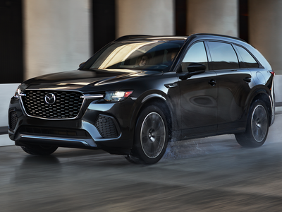 Black Mazda SUV driving on a road with a blurred background
