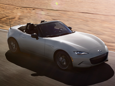 White convertible car driving on a road with a blurred background